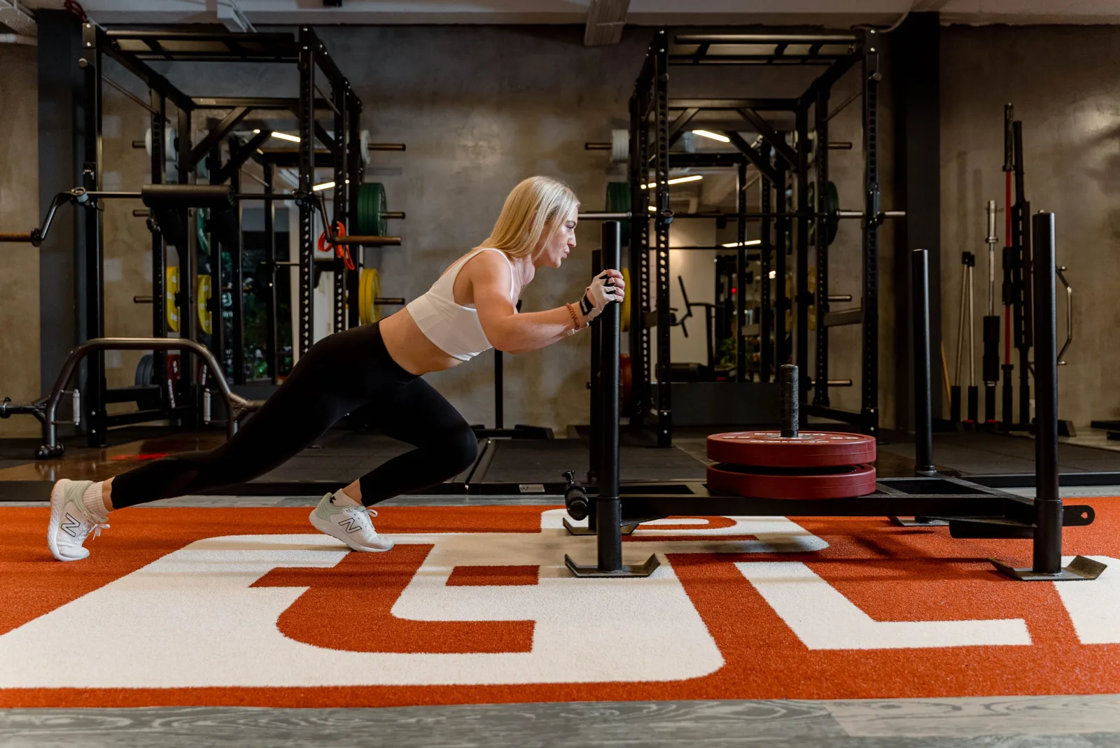 Athletin schiebt einen beladenen Schlitten im Gym